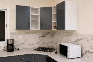 a kitchen with gray cabinets and a microwave on a counter at Villas avec piscine in Taguermess +3 photos