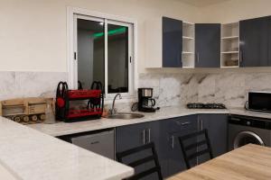 a kitchen with blue cabinets and a counter top at Villas avec piscine in Taguermess