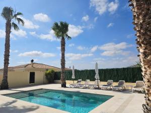 a swimming pool with chairs and palm trees at Villa - Sleeps 4 - Pool - Patio - Parking in Arboleas