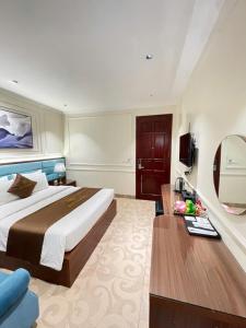 a bedroom with a bed and a table and a mirror at Grand Hotel & Spa Bac Ninh in Ðồng Ky