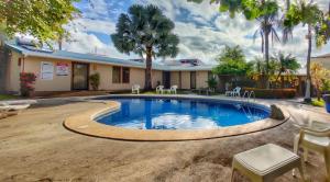 a pool in a yard with chairs and trees at Hotel La Punta in Puntarenas