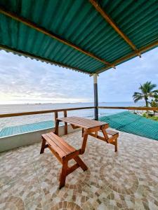 a picnic table and bench under a green umbrella at Suite frente al Mar con Acceso Directo a la Playa in Ballenita