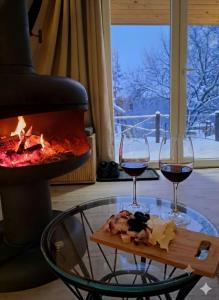 two glasses of red wine next to a fireplace at A frame ti i ja in Smederevska Palanka