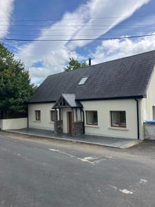 a white house with a black roof on a street at An Cnocán in Limerick