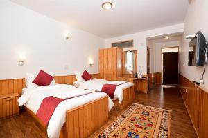 a bedroom with two beds and a television in it at Hotel Karakoram in Leh