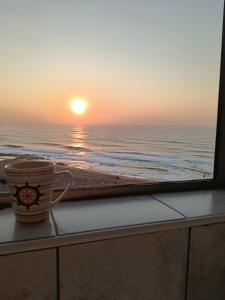 a coffee cup sitting on a window sill looking at the ocean at Peacehaven's Top Floor Gem 703 in Scottburgh