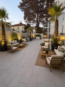 a patio with couches and chairs and palm trees at hotel Torretta Bramante in Rimini
