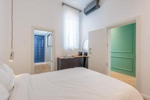 a bedroom with a white bed and a green door at Casa Lola in Mellieħa +12 photos