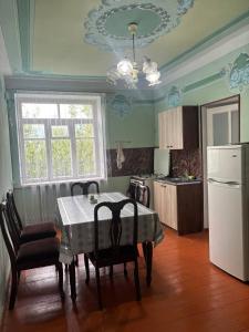 a kitchen with a table with chairs and a white refrigerator at Meronc Mot Guesthouse in Stepʼanavan