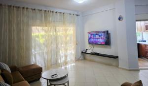 a living room with a couch and a tv on a wall at Casa Kaçi in Mullini i Danit