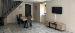 a dining room with a table and chairs and a tv at Gîte Le Citronnier - Piscine partagée in Lagorce
