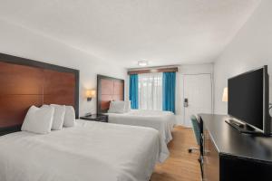 a hotel room with two beds and a flat screen tv at Pine Tree inn in Medford