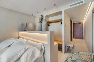 a bedroom with a white bed and a chair at Suites by Miramar - Adults only in Lloret de Mar