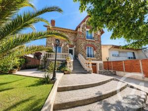 a house with a palm tree in front of it at Livry Gargan in Livry-Gargan