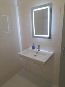 a white bathroom with a sink and a window at Residence du fromager in Bouaké