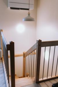a stairway with a wooden rail and a light at Lavandas apartamenti in Ikšķile