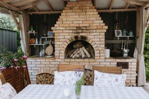 a brick fireplace in a patio with a table and chairs at Lavandas apartamenti in Ikšķile