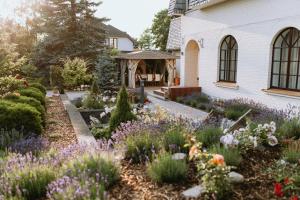 a garden in front of a house with flowers at Lavandas apartamenti in Ikšķile