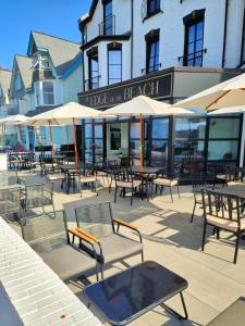 an outdoor patio with tables and chairs and umbrellas at The Edge Of The Beach in Bude