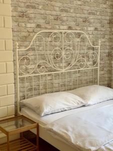 a bed with a metal headboard next to a brick wall at Cent Hostel - Lublin Centrum in Lublin