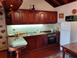a kitchen with wooden cabinets and a white refrigerator at Casita Roque Nublo in Tejeda