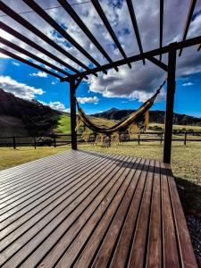 a wooden deck with a hammock and a field at Cabanas Céu e Mel - Cabana 01 in Bom Retiro