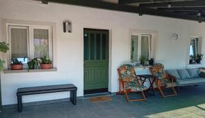 a porch with a green door and a couch and chairs at APARTMA BrdonKA in Dobrovo