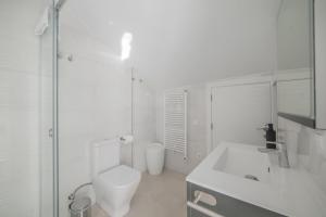 a white bathroom with a toilet and a sink at Principado de Aracena I in Aracena