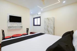 a bedroom with a bed and two chairs and a tv at Hotel O Swarg Paradise Inn in Rānchī +21 photos