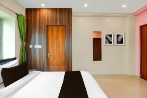 a bedroom with a bed and a wooden door at Hotel O Newtown worldstay in Thākurdwari +23 photos