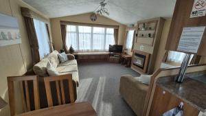 a living room with a couch and a television at Camber Sands Holiday Park in Camber