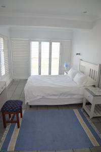 a bedroom with a white bed and a blue rug at 87 Marine Drive in Struisbaai