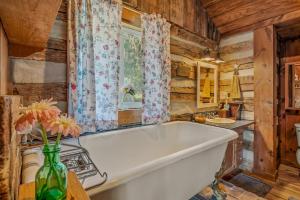 a white bath tub in a kitchen with wooden walls at Pondview Cabin - Rustic Log Style Home, Grill, Wifi, Screen Porch, Trail, View, Pond Access, King Bed in Morton Grove +42 photos