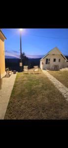 a house with two chairs in a yard with a light at Jezerina in Šavnik