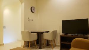 a living room with a table and a tv and chairs at Alzahraa apartment in Salalah