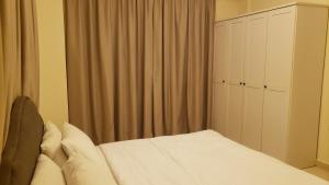 a bedroom with a white bed and a closet at Alzahraa apartment in Salalah