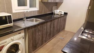 a kitchen with a sink and a washing machine at Alzahraa apartment in Salalah