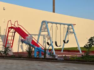 a playground with two swings and a slide at أستراحة الهوني in Banghāzī