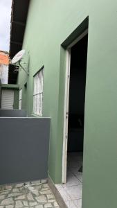 a green building with an open door and a hallway at Casa Aconchegante com 2 quartos in Araçariguama