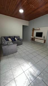 a living room with a couch and a tv at Casa Aconchegante com 2 quartos in Araçariguama