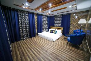 a bedroom with blue curtains and a bed and a chair at Royal Brangsa in Skardu +23 photos