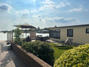 a house with a patio with a table and an umbrella at VISSERSLUST Rooms, Apartments and Houseboats in Vinkeveen