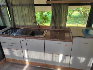 a kitchen with white cabinets and a sink and a window at terrebioBus in Visnadello