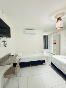 a white room with two beds and a table and a chair at Pousada Costamar in Maragogi