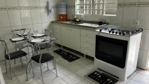 a kitchen with a stove and a table with chairs at Casa Aconchegante com 2 quartos in Araçariguama
