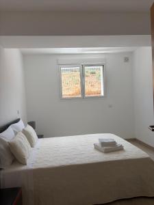 a white bedroom with a large bed with two windows at Alojamento das cantarinhas in Bragança