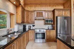 a kitchen with wooden cabinets and a stainless steel refrigerator at Fiddler Lake Resort - Elk 96 in Mille-Isles