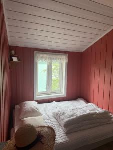 a bedroom with pink walls and a bed with a window at Vetleberget - simple living in Vaga