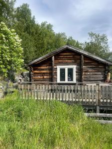 a log cabin with a fence in front of it at Vetleberget - simple living in Vaga