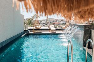 a swimming pool with chairs and a water fountain at WG Hotel Lake View in Ksamil